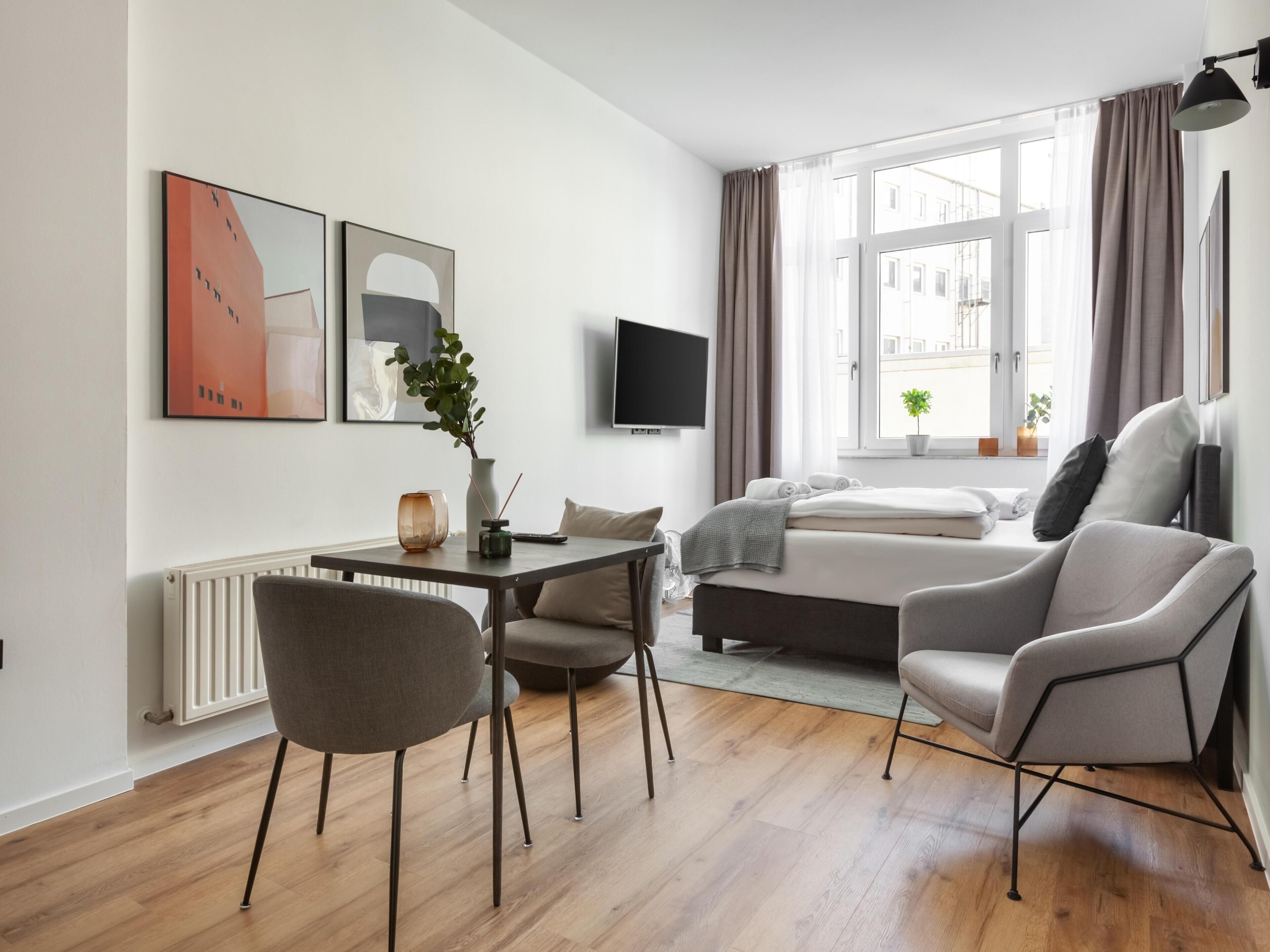 A modern living room with a sofa, a dining table, and a TV.