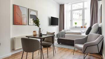 A modern living room with a sofa, a dining table, and a TV.