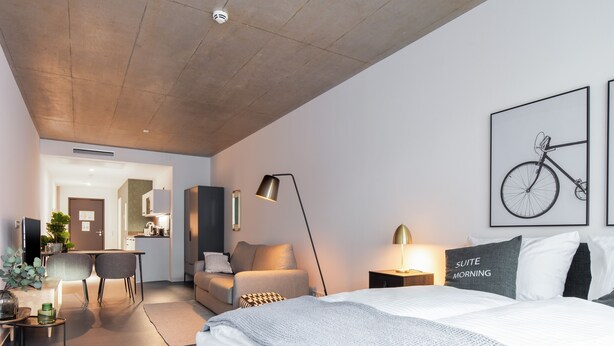 A modern hotel room with a large bed, a desk, and a kitchenette. - Limehome Erfurt Maximilian-Welsch-Str. (Erfurt)