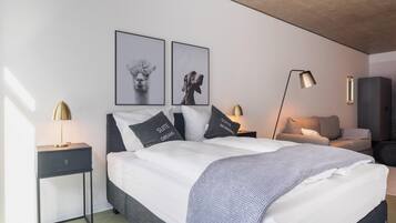 Een moderne slaapkamer met een bed, nachtkastjes, een vloerlamp en kunst aan de muur.