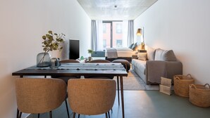 A modern, compact living space with a dining area, a sofa, a bed, and a TV. - Limehome Erfurt Maximilian-Welsch-Str. (Erfurt)