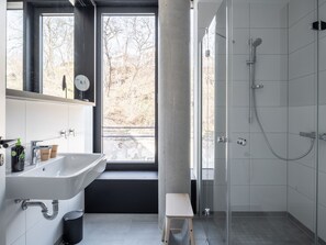 A modern bathroom with a large window, a sink, a shower, and a small stool. - Limehome Erfurt Maximilian-Welsch-Str. (Erfurt)
