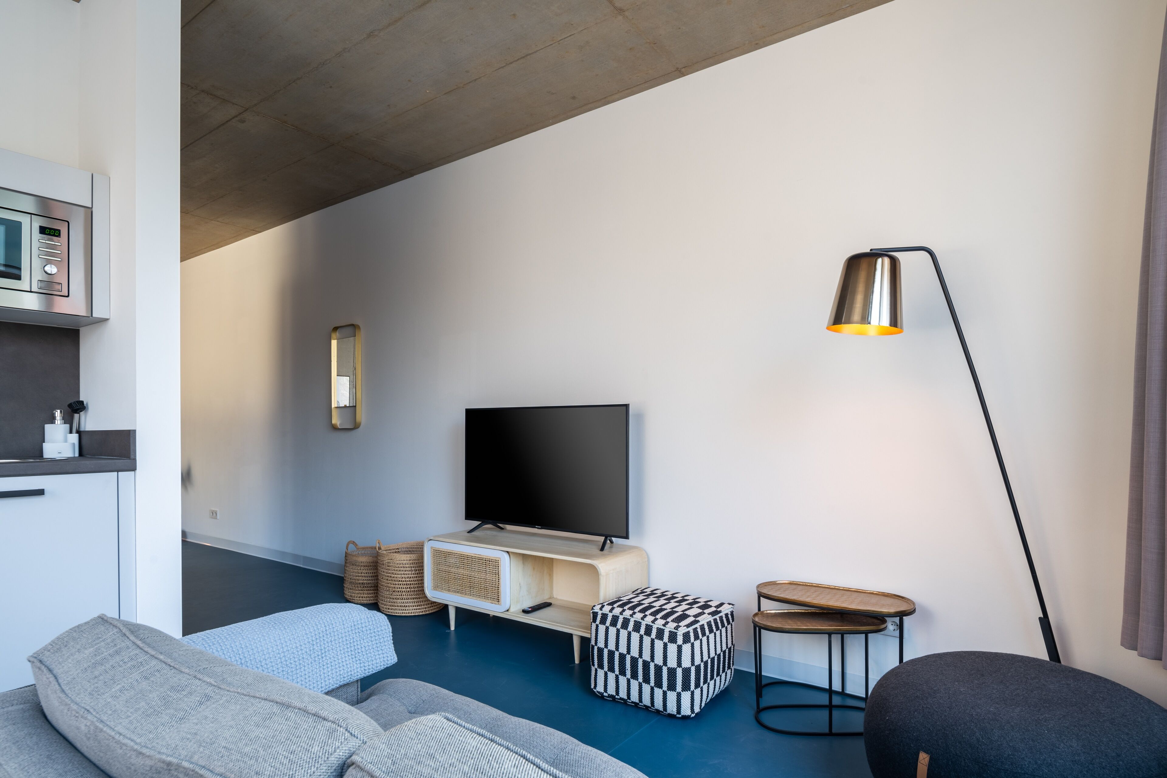 Una sala de estar moderna con un televisor de pantalla plana, un sofá, una mesa de centro y una lámpara de pie.