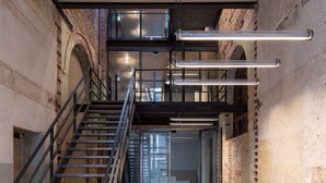 A staircase leading to a mezzanine level in a building with exposed brick walls and metal railings. - Limehome Erfurt Maximilian-Welsch-Str. (Erfurt)