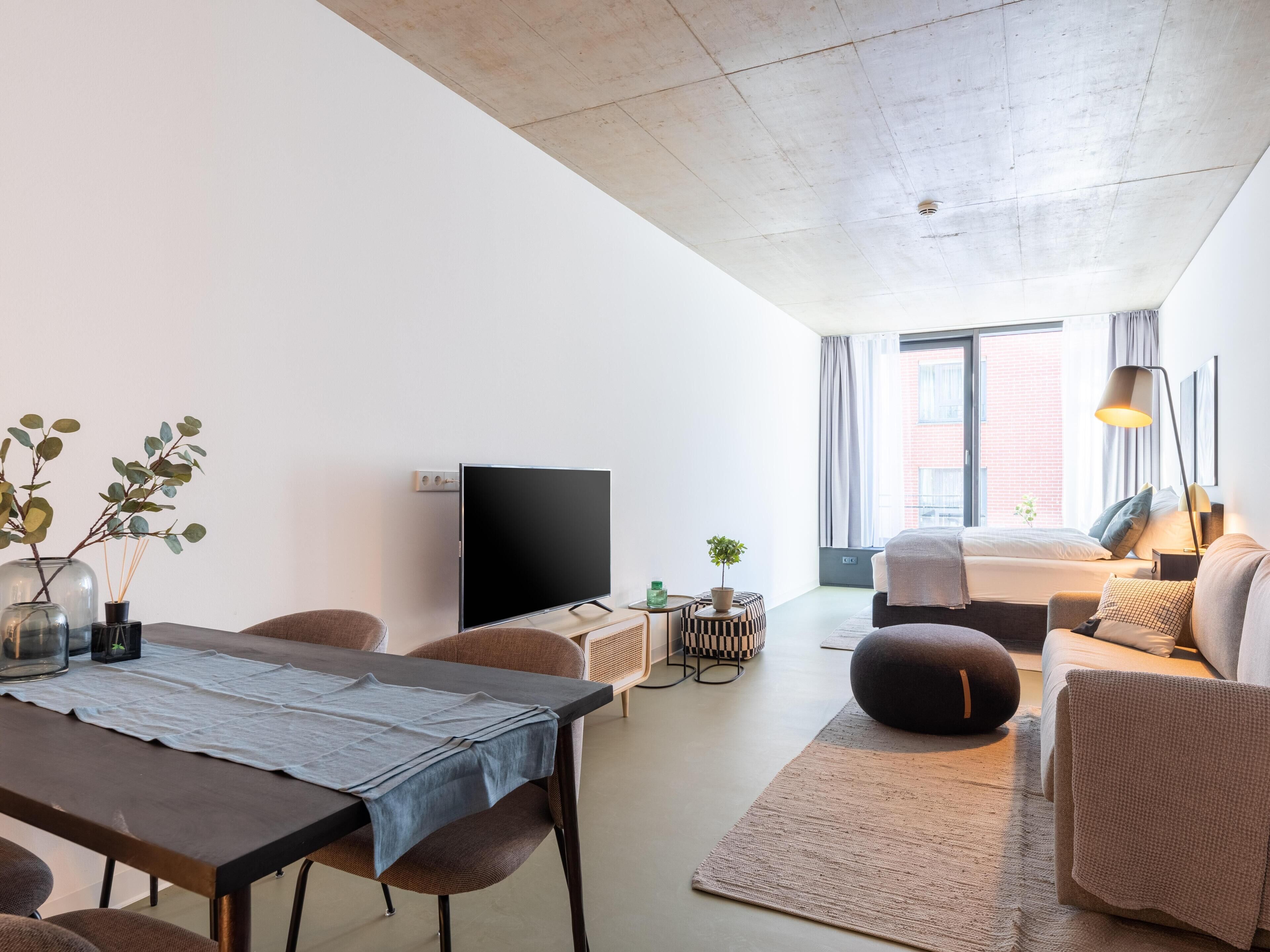 Ein modernes Wohnzimmer mit Flachbildfernseher, Esstisch und einer Couch.