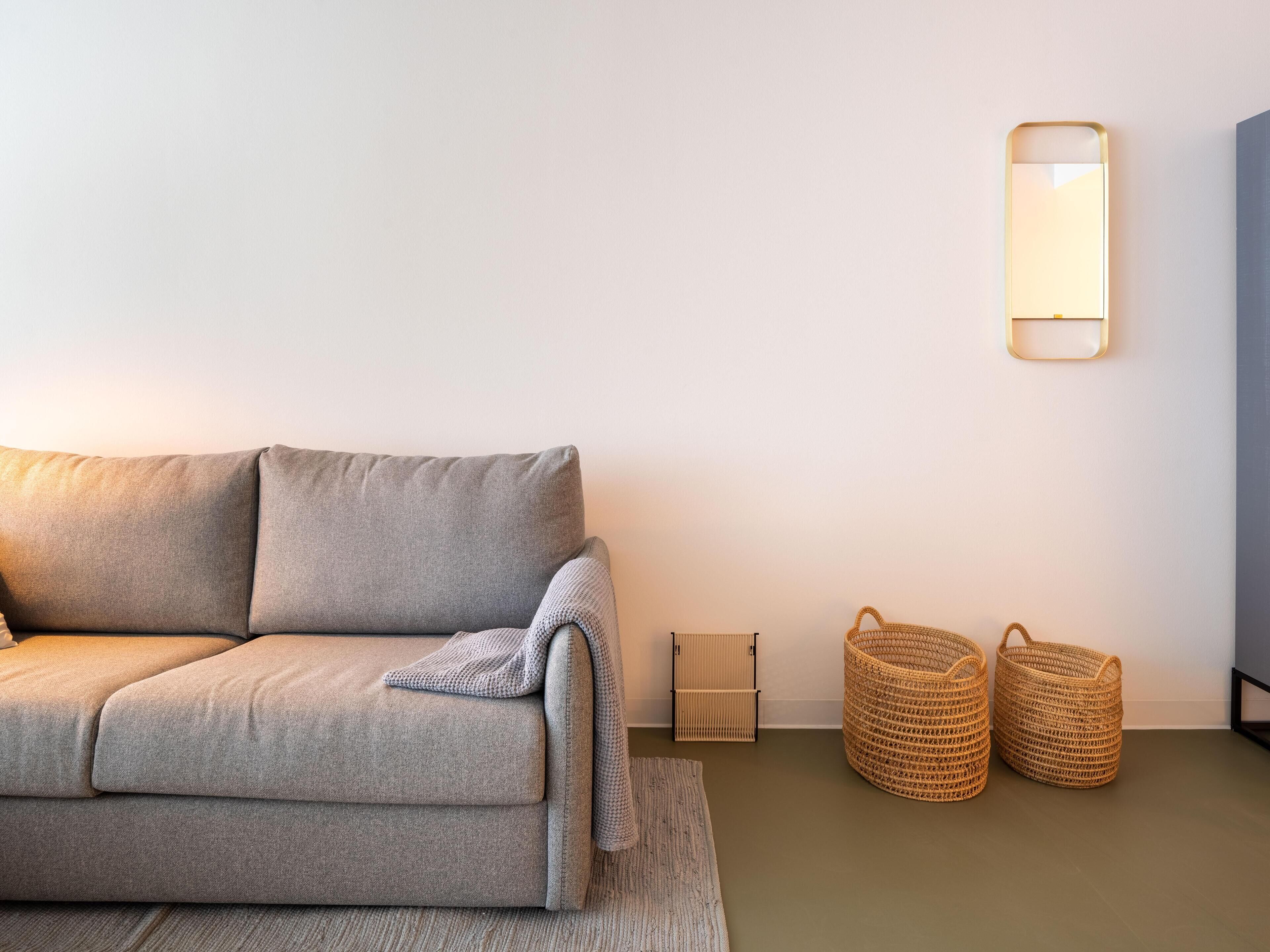 Uma sala de estar moderna com um sofá cinza, uma mesinha lateral e duas cestas trançadas.