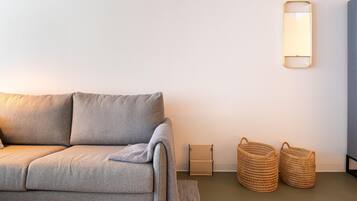Uma sala de estar moderna com um sofá cinza, uma mesinha lateral e duas cestas trançadas.