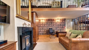 A spacious living room with a fireplace, leather sofa, and a large bookshelf. - Carnegie Library Bronte Apartment (Swinton)