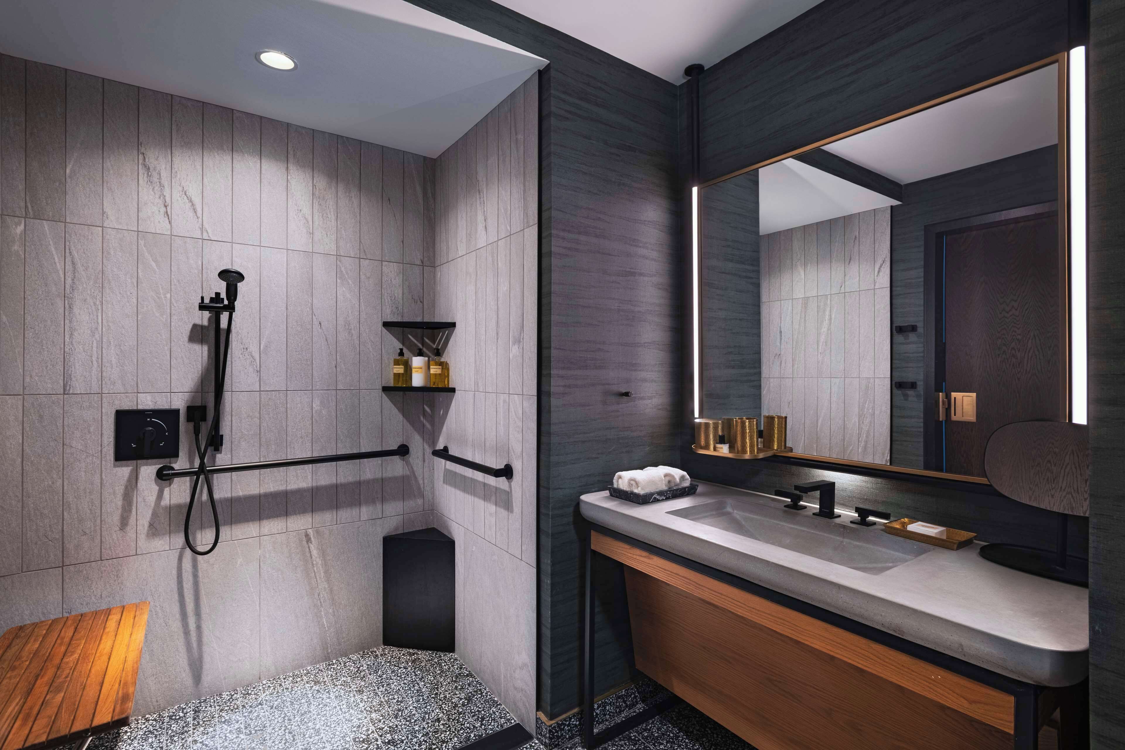 A modern bathroom with a wooden vanity, a large mirror, and a shower area.
