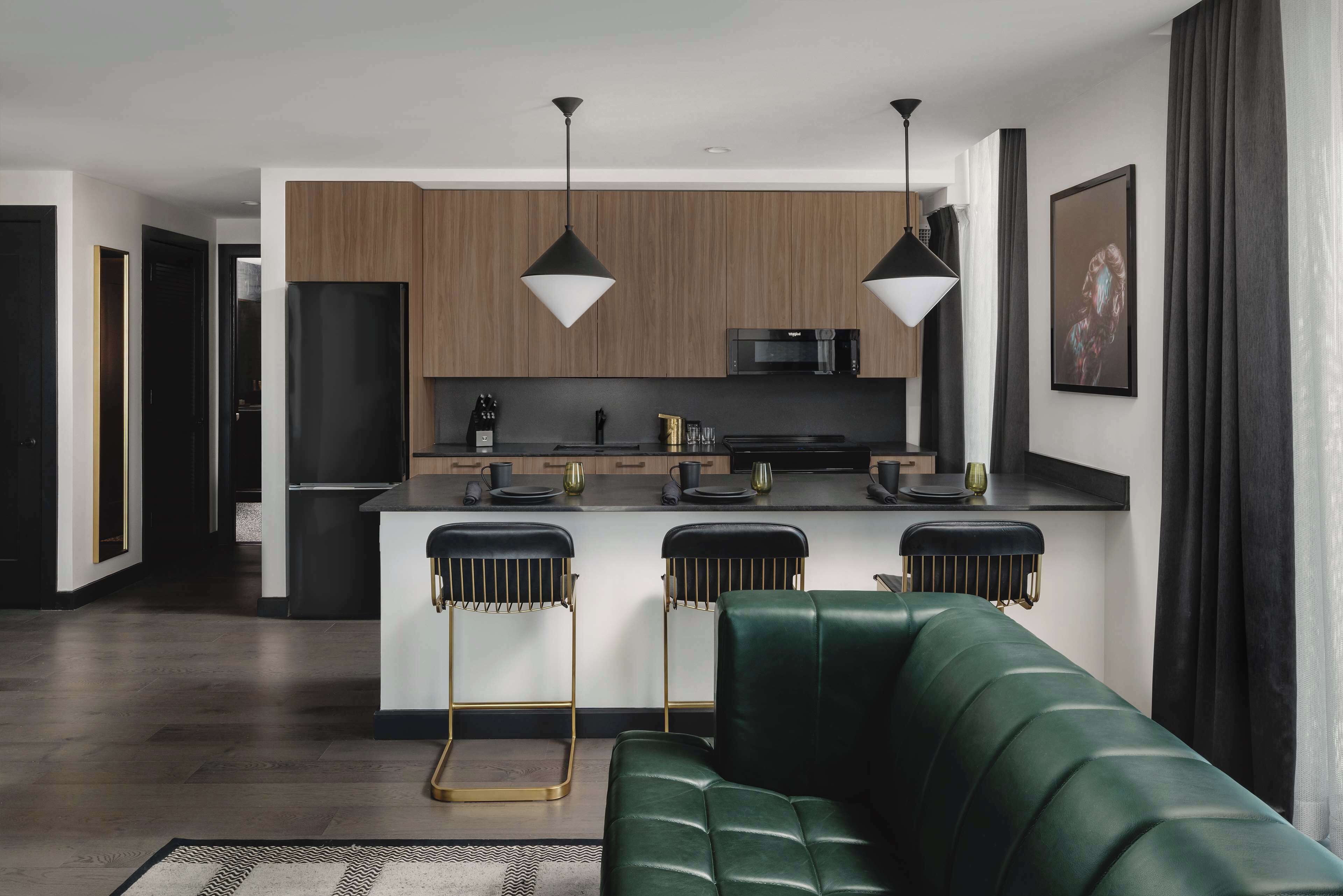 A modern kitchen with a central island, bar stools, and pendant lighting.