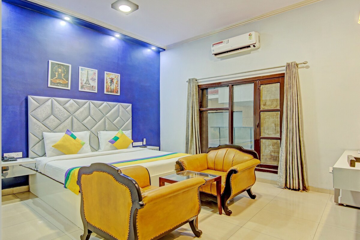A hotel room with a bed, a sofa, a small table, and a window with curtains.