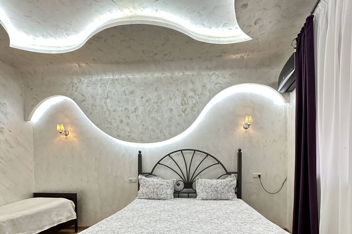 A bedroom with a bed, a nightstand, and a wall-mounted lamp.