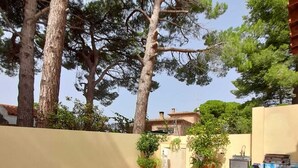 A swimming pool with tiled flooring, surrounded by trees and a building in the background. - Villa de Rêve à 200 Mètres de la Plage de Riells (L'Escala)