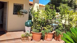 A courtyard with potted plants, a tiled floor, and a building with a tiled roof and window. - Villa de Rêve à 200 Mètres de la Plage de Riells (L'Escala)
