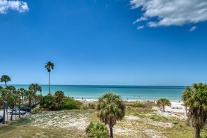 Ein Strand mit Palmen, blauem Himmel und ruhigem Meer.