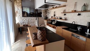 A modern kitchen with a central island, wooden cabinets, and a stone wall. - Authentic House, near Uzès, amazing view (Le Pin)