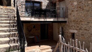 A stone building with a balcony, outdoor seating, and a wooden fence. - Authentic House, near Uzès, amazing view (Le Pin)