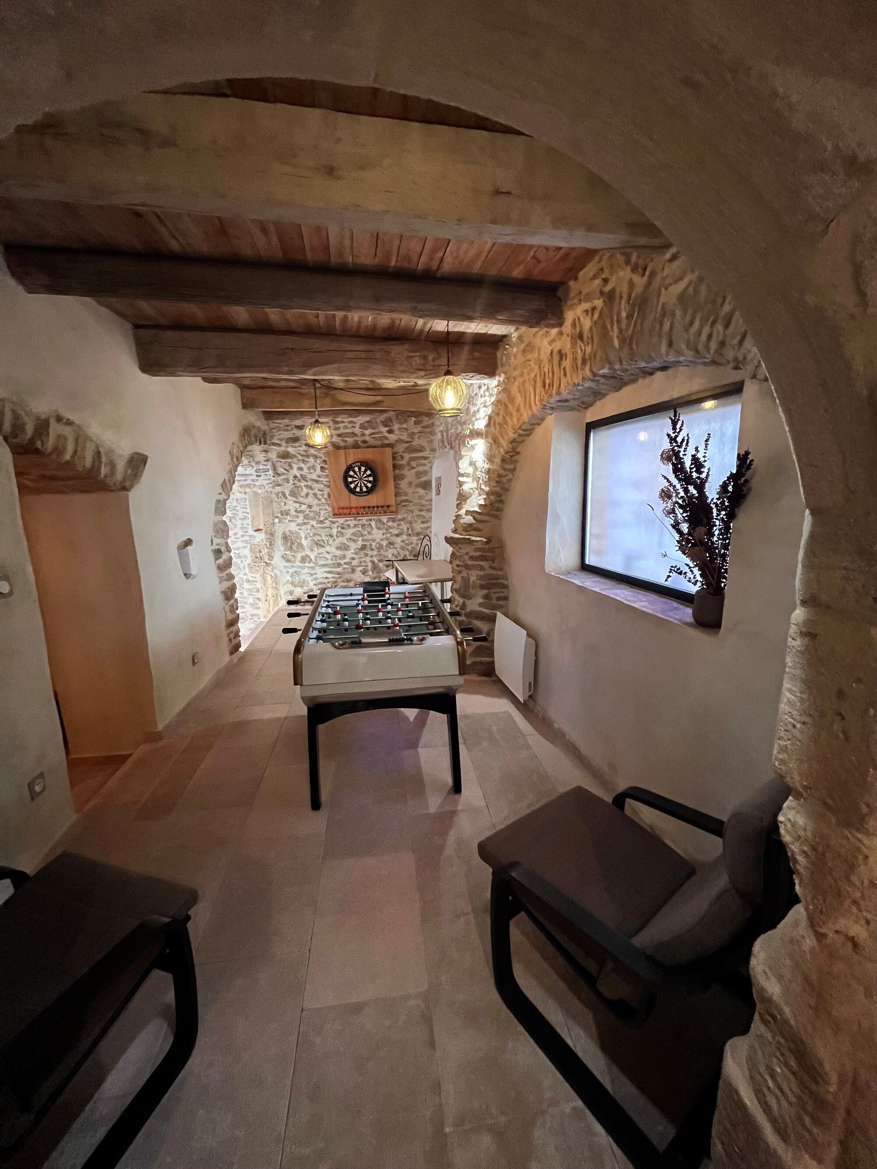 A cozy room with a foosball table, a dartboard, and a window with a view.