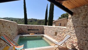 A wooden deck with a pool, lounge chairs, and a stone wall. - Authentic House, near Uzès, amazing view (Le Pin)