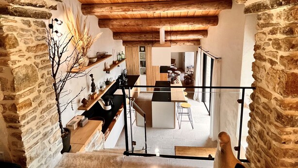 A stone archway leading to a dining area with a view of the kitchen and living space. - Authentic House, near Uzès, amazing view (Le Pin)