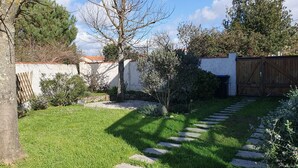 Ein gepflegter Garten mit einem Kiesweg, einem Holzzaun und verschiedenen Sträuchern.