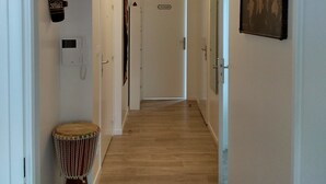 Un couloir avec un plancher en bois, une porte portant l’inscription « CHAMBRE », un téléphone fixé au mur et une batterie.