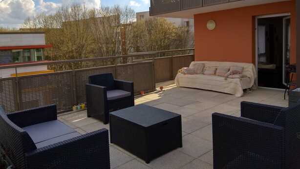 Un balcon agrémenté de meubles en osier, d’un canapé et d’une table.