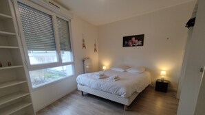 Une chambre à coucher comprenant un lit, des lampes de chevet, une fenêtre et une œuvre d’art accrochée au mur.