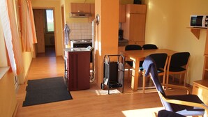 Cocina compacta con microondas, estufa y armarios. Cuenta con un comedor con mesa y sillas.