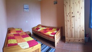 Un dormitorio con dos camas de madera, un armario grande y un cuadro pequeño en la pared.