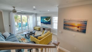 A spacious living room with a large TV, comfortable seating, and a balcony with outdoor furniture. - ♥ BEACH CONDO ♥ NEW ♥ SLEEPS 10 ♥ 3 BD 2.5 BA ♥ U4 (Indian Rocks Beach)