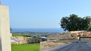 Eine Außenpatio mit Steinmauern, einem Tisch mit Stühlen und Blick auf das Meer.