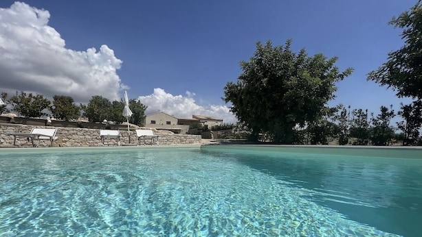 Ein klares Schwimmbecken mit Liegestühlen und einer Steinmauer.