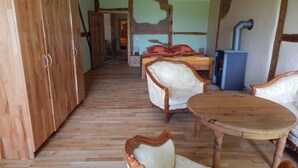 Une pièce comprenant une armoire en bois, un lit recouvert d’une couverture colorée, une table en bois et une chaise.