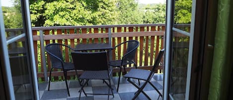 A balcony with a checkered floor, a wooden railing, and a table with four chairs.