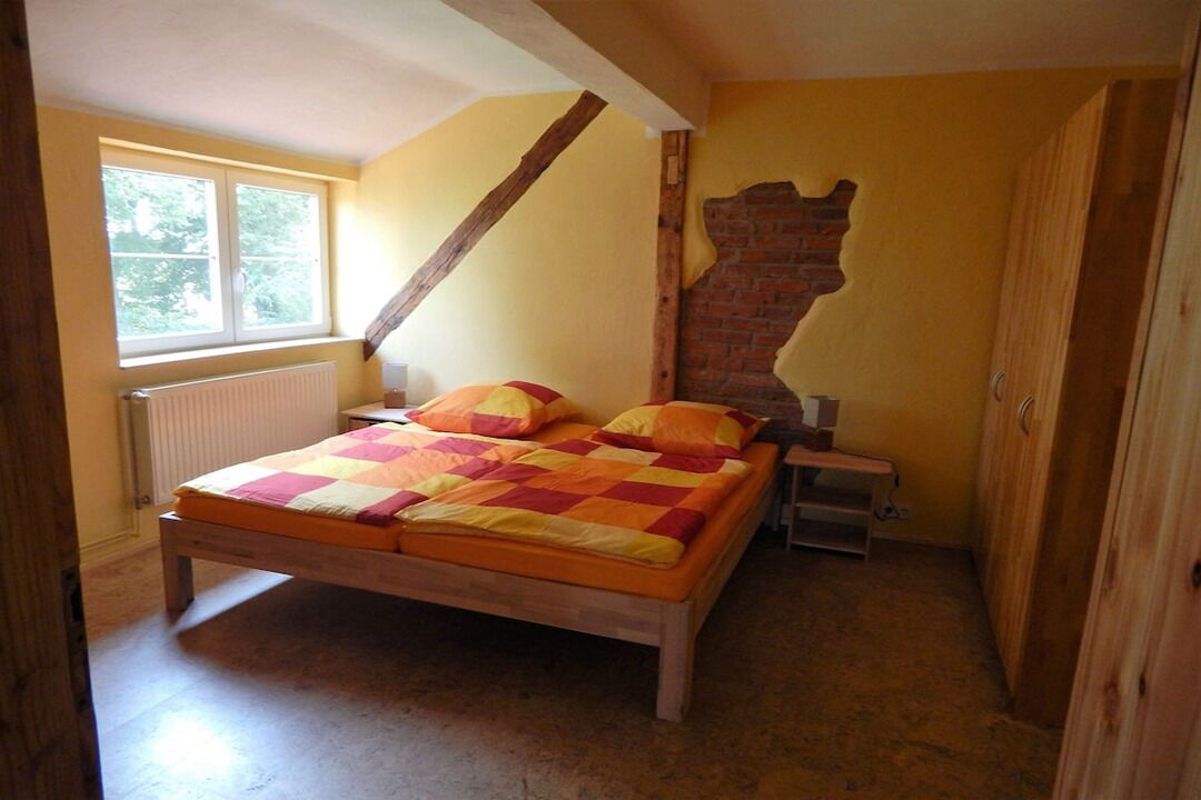 Een slaapkamer met een houten bed, een wand van bakstenen en een raam.