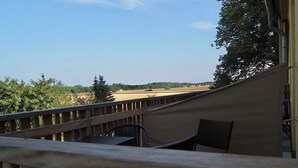Un balcon donnant sur un champ et une tour située au loin.