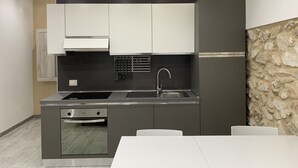Eine moderne Küche mit grauen Schränken, einem eingebauten Backofen und einer Wand mit Steinverkleidung.