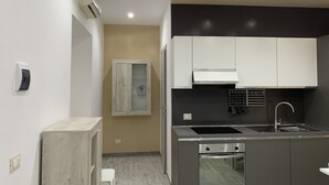 Eine kompakte Küche mit Einbauofen, Spüle und Herd. Es gibt einen Holzkasten mit Glastür und einen weißen Schrank darüber.