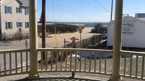 En overdækket veranda med udsigt over en strand og et motel-skilt.