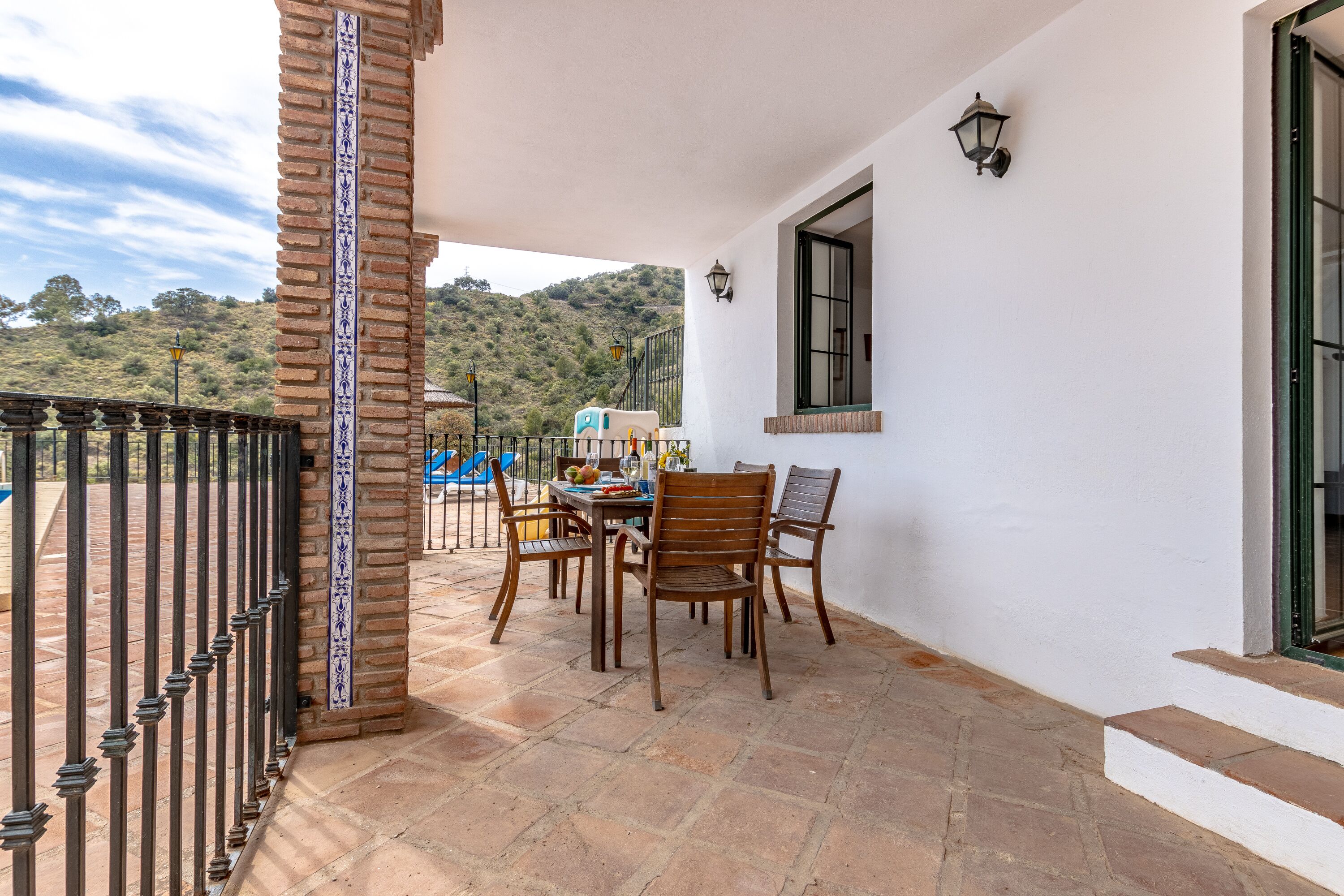 Une terrasse avec une table et des chaises, un pilier en briques et une vue sur les collines.