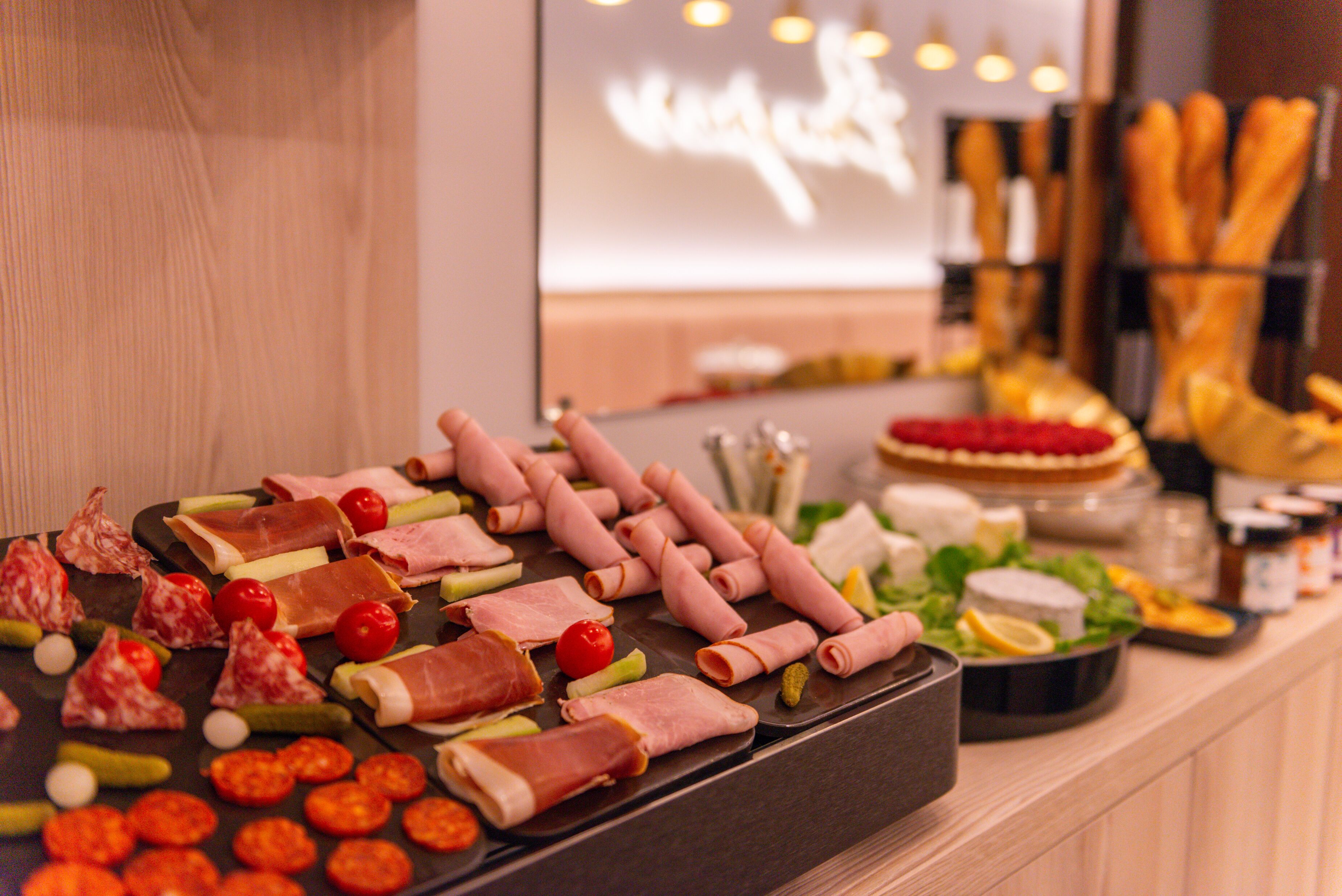A buffet with various meats, cheeses, and vegetables.