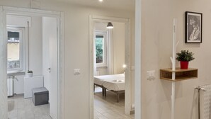 Ein Flur mit Bett, einem kleinen Tisch, einer Topfpflanze und einer Heizung.