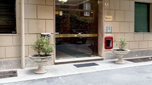 Ein Gebäudeeingang mit Glastür, zwei Topfpflanzen, einem Schild für die Reiseinformation und einem roten Briefkasten.