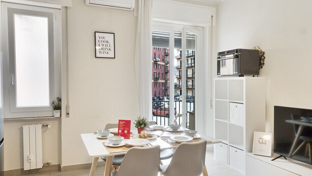 Eine moderne Küche mit Esstisch für vier Personen, einem eingebauten Backofen und Blick auf die Stadt durch das Fenster.