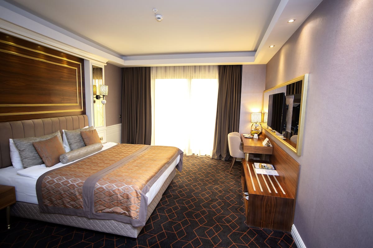 Ein Hotelzimmer mit einem großen Bett, einem Schreibtisch, einem Stuhl und einem Spiegel.