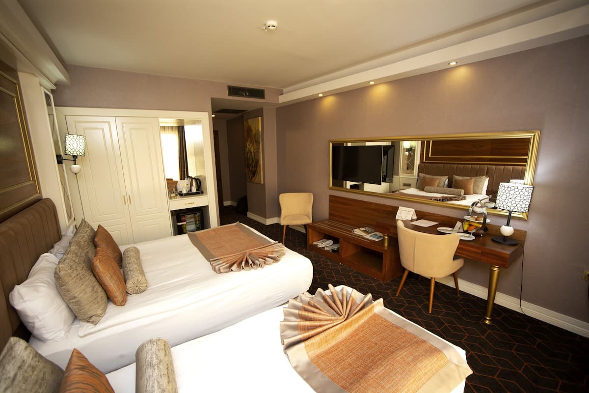 Ein Hotelzimmer mit zwei Betten, einem Schreibtisch, einem Stuhl, einem Spiegel und einem Kleiderschrank.
