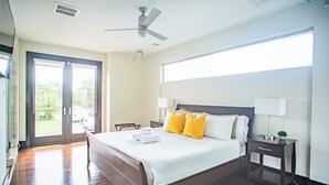 Ein Hotelzimmer mit einem großen Bett, zwei Nachttischlampen, einem Deckenventilator und Blick durch die Glastüren.