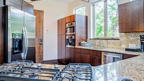 Eine moderne Küche mit Edelstahlgeräten, Holzschränken und einer Arbeitsplatte aus Granit.