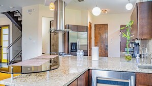 Eine moderne Küche mit Granit-Arbeitsplatten, Edelstahlgeräten und Holzschränken.